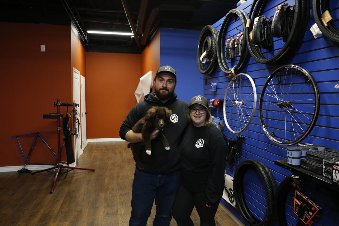 Owner and a team member in matching Z hoodies holding puppy Mojo in front of a wall of tires